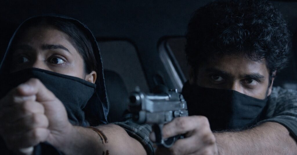 Dacoit movie action scene with Adivi Sesh and Mrunal Thakur holding gun inside car